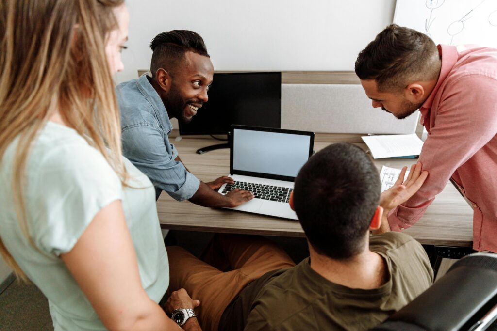 pexels-photo-5257759-5257759 Four colleagues brainstorming around a laptop in a bright, modern office setting.