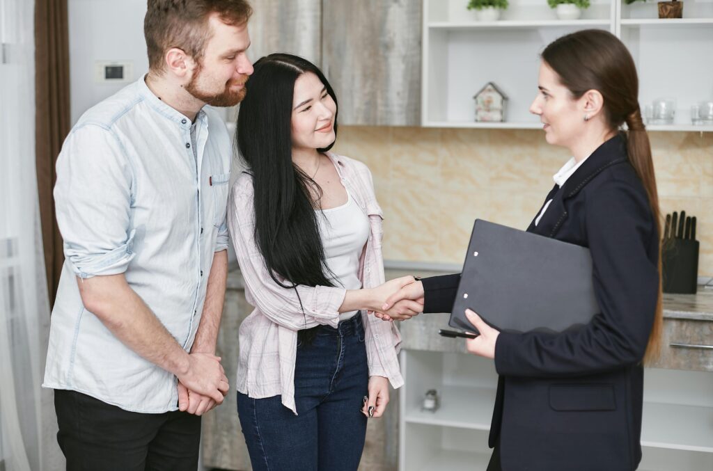 pexels-photo-7734597-7734597 A young couple shakes hands with a real estate agent during a home tour or negotiation in a modern setting.